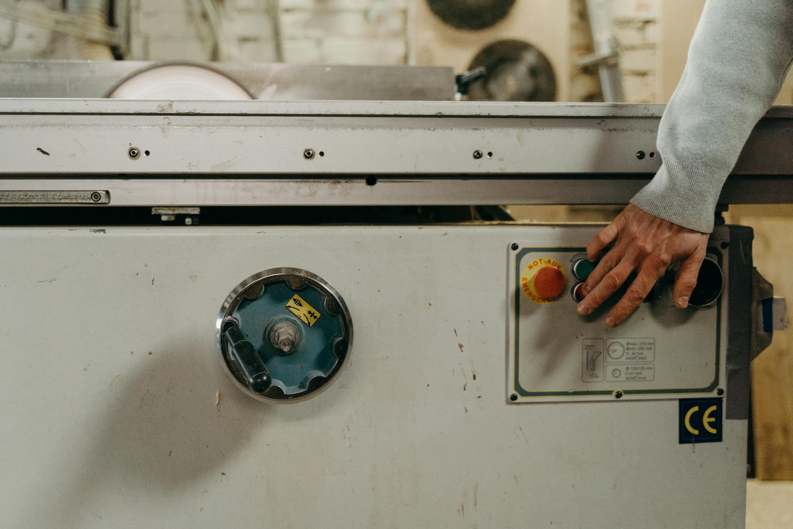 Close-up of a carpenter's hand operating a circular saw in a woodshop.